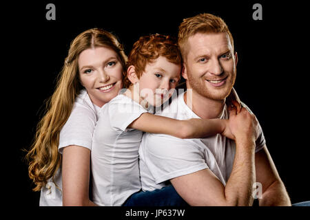 portrait of family in white t-shirts hugging each other isolated on black Stock Photo