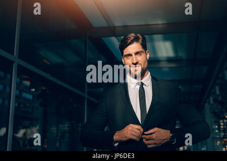 Portrait of handsome young man in business suit looking at camera. He is standing in a modern building. Stock Photo