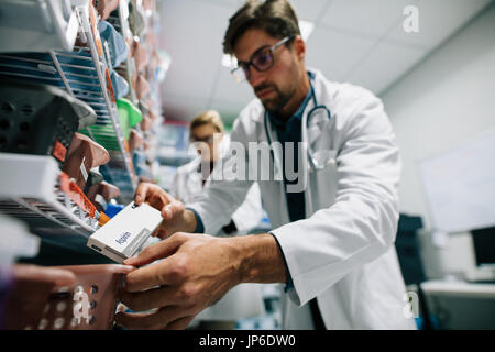 Pharmacist looking for a drug on shelf. Male pharmacist checking stock in an shelf. Medical staff working in hospital pharmacy. Stock Photo