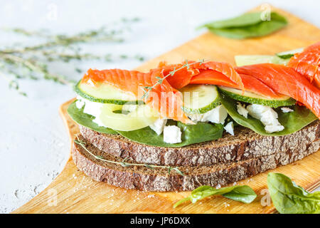 sandwich with smoked salmon, vegetables and curd cheese on a wooden board. Stock Photo