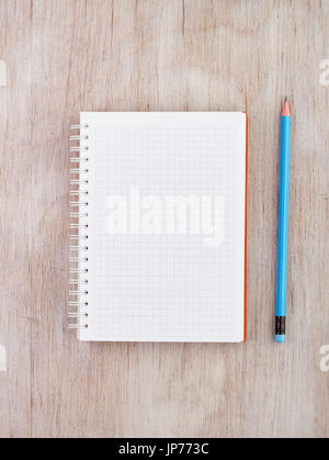 Top view of empty white notebook with spiral and blue pencil on wooden desk. Place for your text Stock Photo