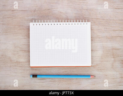 Top view of empty white notebook with spiral and blue pencil on wooden desk. Place for your text Stock Photo