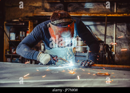 Young man with protective goggles welding in a factory Stock Photo
