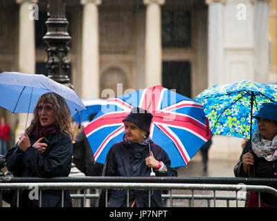 Horizontal portrait of ladies holding umbrellas in the pouring rain. Stock Photo