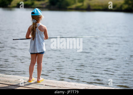 Young fisherman fishing on lake or river. Guy stand alone and hold