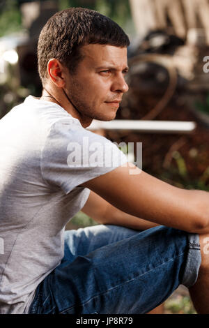 Outdoor portrait of a handsome young man in jeans and gray t-shirt. Stock Photo