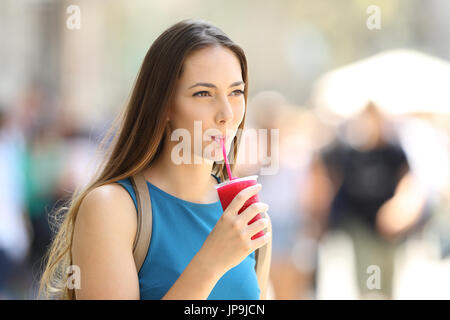 Single girl walking and sipping a slush in the street in summer Stock Photo