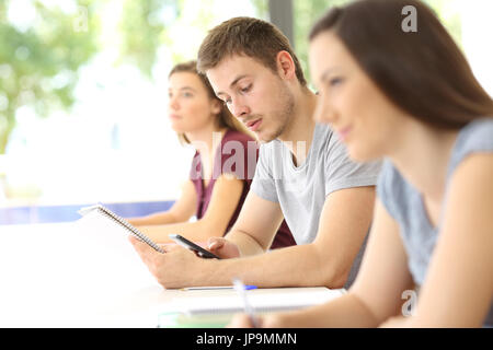 Student distracted with a mobile phone during a class in a classroom Stock Photo