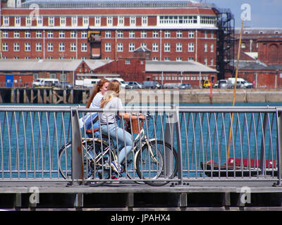 Two girls ride bicycles along the Millennium pier in Gosport, Hampshire Stock Photo