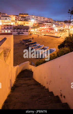 Boats on sandy beach frame the typical fishing village of Carvoeiro at dusk Lagoa Municipality Algarve Portugal Europe Stock Photo