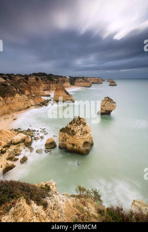 Dark clouds on cliffs framed by the turquoise ocean Praia da Marinha Caramujeira Lagoa Municipality Algarve Portugal Europe Stock Photo
