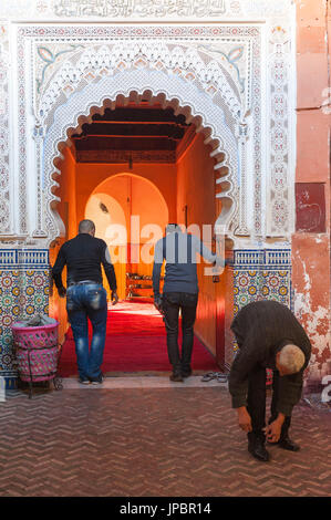 Marrakech, Morocco. Men taking off their shoes at the entrance of a mosque. Stock Photo