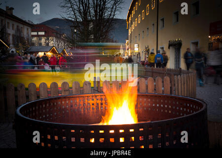 an image of a bonfire with a little train passing behind the fire, during the Christmas market in the city of Bruneck, Bolzano province, South Tyrol, Trentino Alto Adige, Italy, Europe Stock Photo