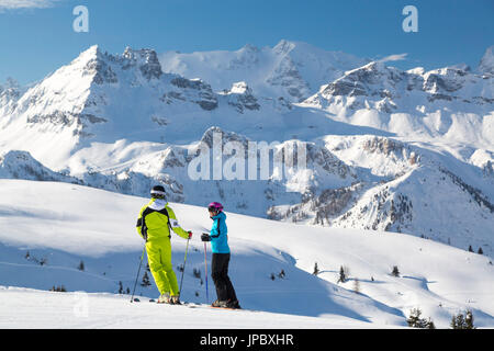 Skiers on ski slopes of Cherz framed by the high peaks of Marmolada and Portavescovo Arabba Dolomites Belluno Veneto Italy Europe Stock Photo