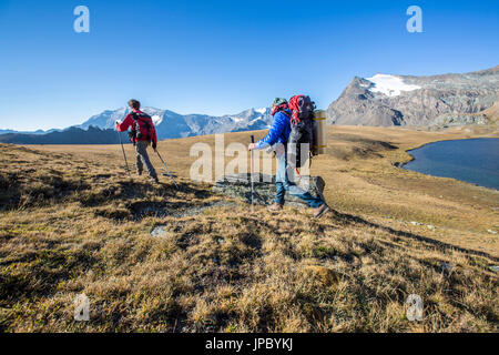 Hikers wallking along Rosset Lake. Gran Paradiso national park. Alpi Graie Stock Photo