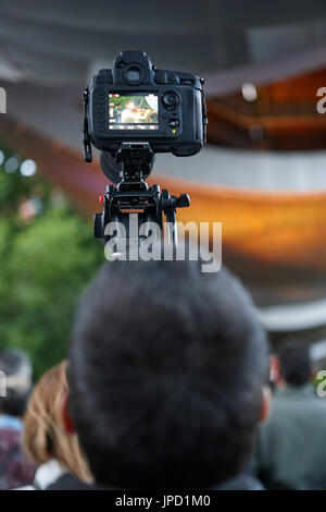 Young man taking photos with a tripod. Outdoors. Vertical Stock Photo