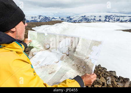 Man with map exploring wilderness on trekking adventure. Stock Photo