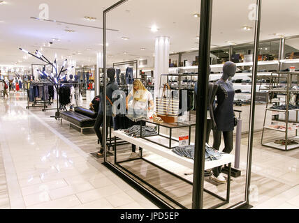 Blonde woman is looking at some denim shorts while talking on the phone in the Macy's department store in Manhattan. Stock Photo