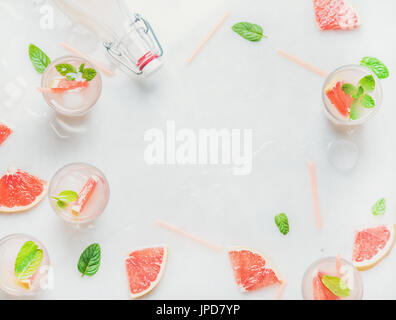 Flat-lay of cold refreshing summer alcohol cocktail with fresh grapefruit, mint and ice in glasses over white marble background, flat-lay, top view, c Stock Photo