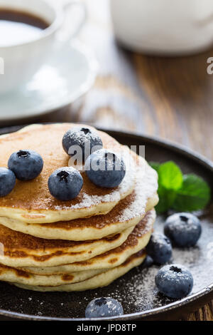 Blueberry buttermilk pancakes in cast iron pan served hot on rustic wooden table, healthy breakfast Stock Photo