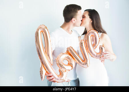 Young happy pregnant woman and man in love on white background. Love and family concept Stock Photo