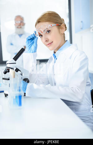 Attractive middle aged scientist working with microscope in chemical lab Stock Photo