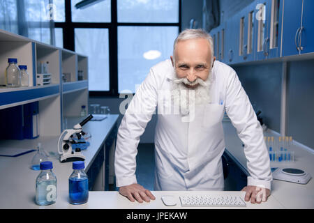 portrait of smiling scientist with hands on table looking at camera in laboratory Stock Photo