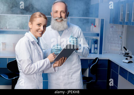 colleagues in lab coats using digital tablet during work at laboratory Stock Photo