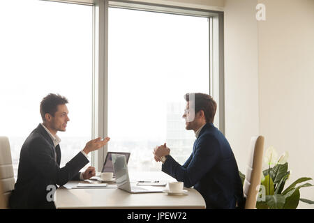 Business meeting of two partners talking and working on laptops Stock Photo