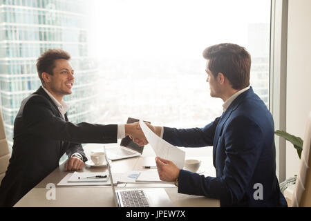 Two businessmen handshaking over office desk, making deal, accep Stock Photo