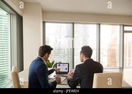 Two businessmen discussing company growth, analyzing rising grap Stock Photo