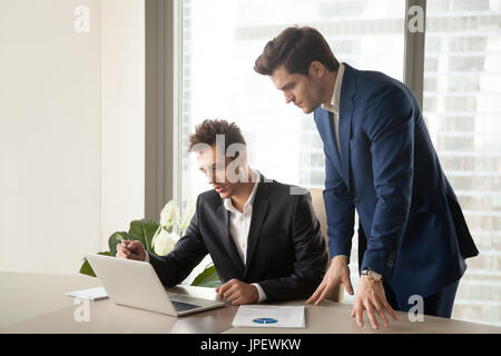 Two serious businessmen looking at laptop screen, working on pro Stock Photo