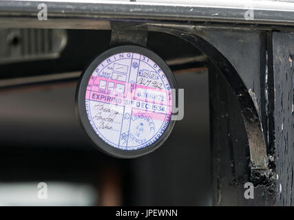 Expired 1930s road tax disc fitted to a vintage Austin 12/4 London taxicab in the UK. Stock Photo