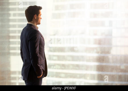 Thoughtful successful businessman looking at city standing in of Stock Photo