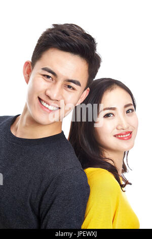 studio portrait of young asian couple, standing back to back, looking at camera smiling, head shot, isolated on white background. Stock Photo