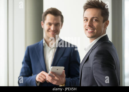 Smiling young businessman looking at camera, application develop Stock Photo