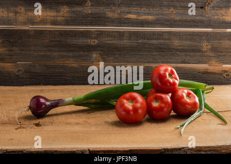 Green onions and tomatoes against the background of old boards Stock Photo