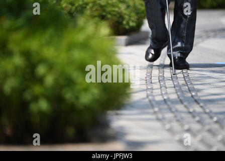 Chongqing, China. 1st Aug, 2017. A blind person walks on stainless steel blind sidewalk in Jiangbei District of Chongqing, southwest China, Aug. 1, 2017. Chongqing improved the accessibility facilities recently so as to build a better city for disabled people. Credit: Wang Quanchao/Xinhua/Alamy Live News Stock Photo