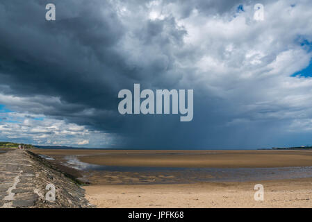 Sunny Summer weather and dramatic dark clouds with intermittent heavy showers over Firth of Forth tidal causeway, Cramond, Edinburgh, Scotland, UK Stock Photo