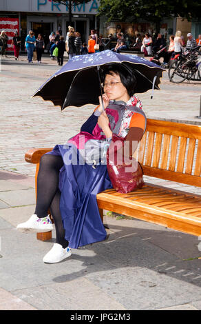 Dundee, Tayside, Scotland, UK. 2nd Aug, 2017. UK weather: A very warm day with the best of the sunshine across Tayside with Maximum temperatures of 19 °C. An East Asian woman seated on the city summer seats sheltering under her brolly from the sunshine enjoying the glorious warm sunny weather in Dundee, Scotland. Credits: Dundee Photographics/Alamy Live News Stock Photo