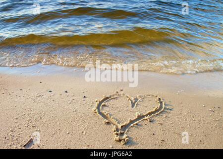 Heart drawn in sand of beach Stock Photo