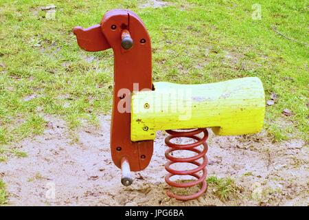 Children colorful wooden swinging dog in playground. Wooden seesaw. Stock Photo