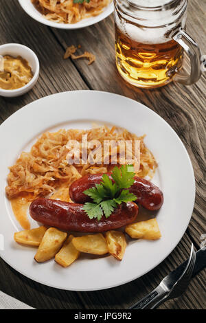 Baked Bavarian sausages with stewed cabbage and a glass of beer Stock Photo