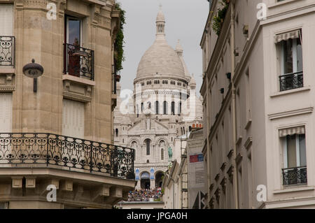 The basilica of the Sacred Heart of Paris (Sacré Coeur) seen in between houses on Boulevard de Rochechouart, Montmartre, Paris, France. Stock Photo