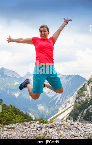 Young pretty woman jumping high in happiness, in mountains Stock Photo