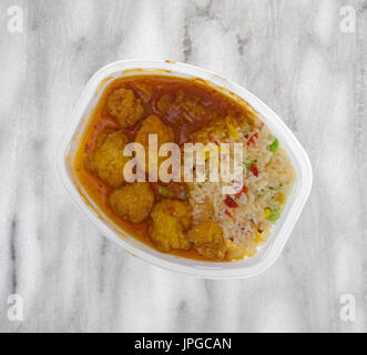 Top view of a cooked chicken nugget TV dinner in a microwavable plastic tray atop a gray marble table top. Stock Photo