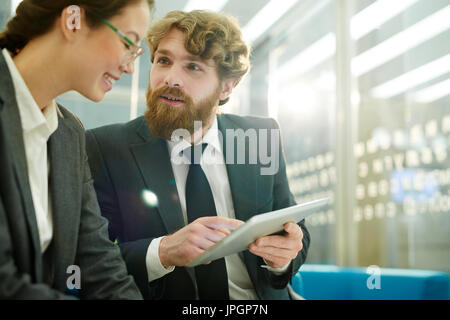 Portrait of two colleagues discussing work project in office using digital tablet Stock Photo