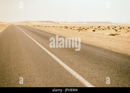 Vintage instagram style image of an empty desert road in Dakhla, Western Sahara desert, Morocco. Stock Photo