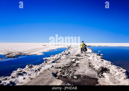Lonely male cyclist travelling through the biggest salar in the world - Salar de Uyuni in Bolivia