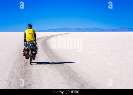 Lonely male cyclist travelling through the biggest salar in the world - Salar de Uyuni in Bolivia